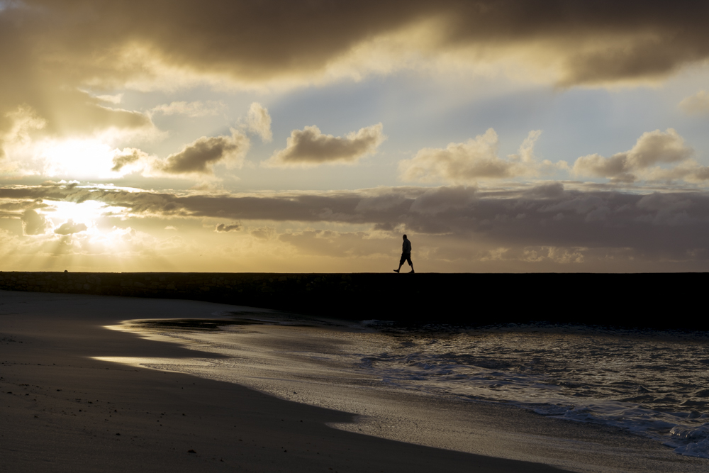 Un homme marche au coucher du soleil sur une jetée à Costa Teguise sur l'île de Lanzarote dans l'archipel des Canaries