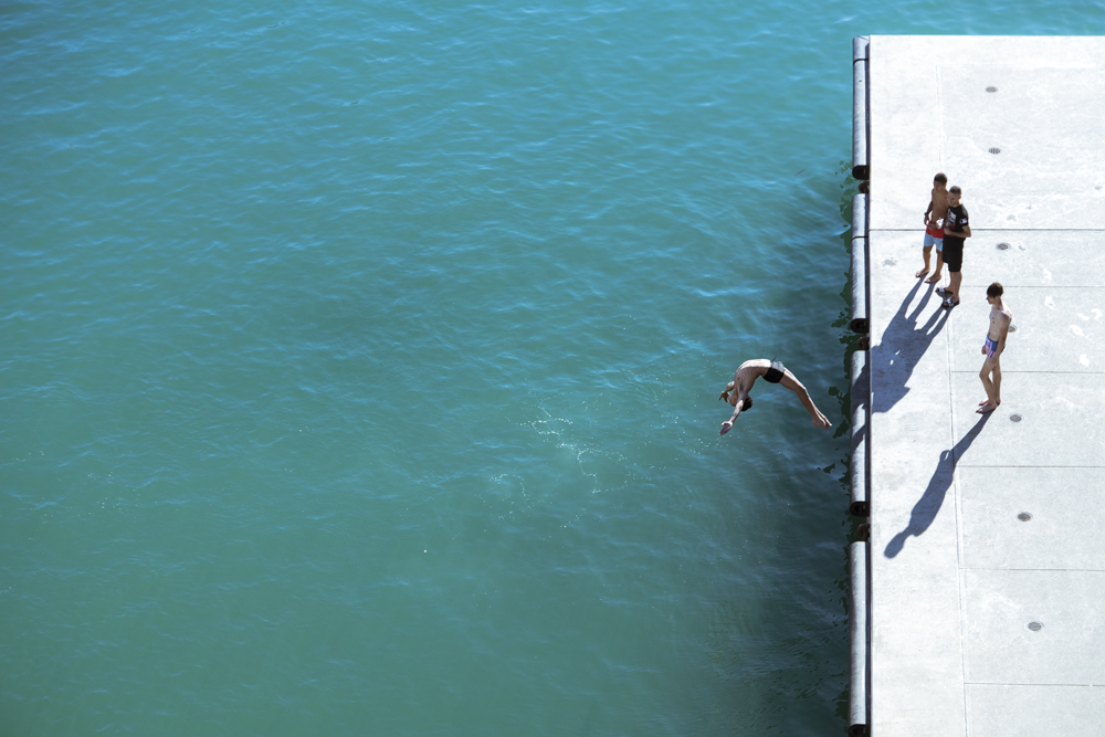 Un adolescent plonge d'un quai longeant le MuCEM, sous le regard de trois de ses camarades.