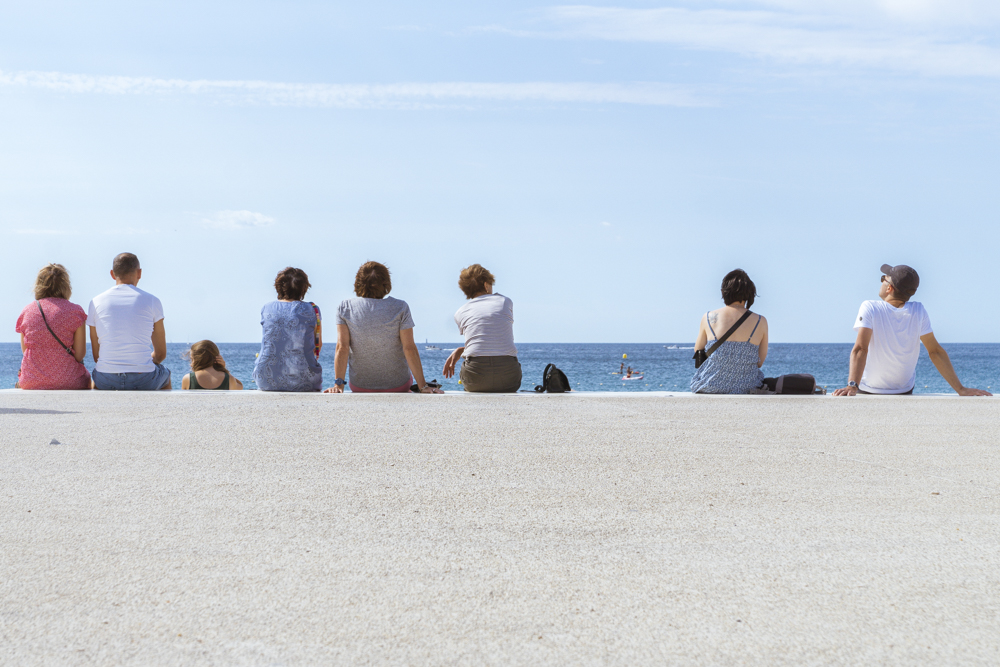 Un groupe de personnes assises face à la mer sur la plage de la Grande Mer. 