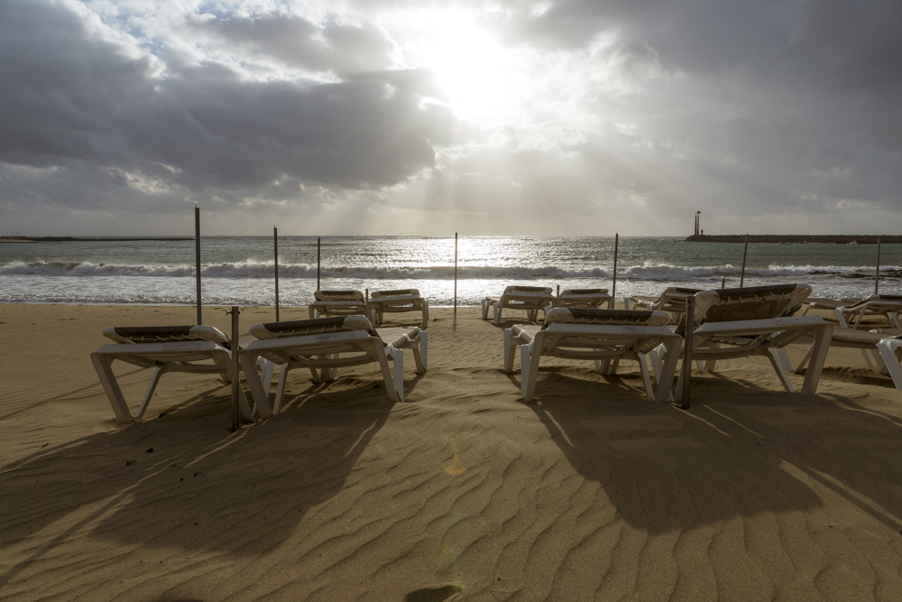 Des transats sur une plage privée d'un hôtel sous un ciel menaçant. 