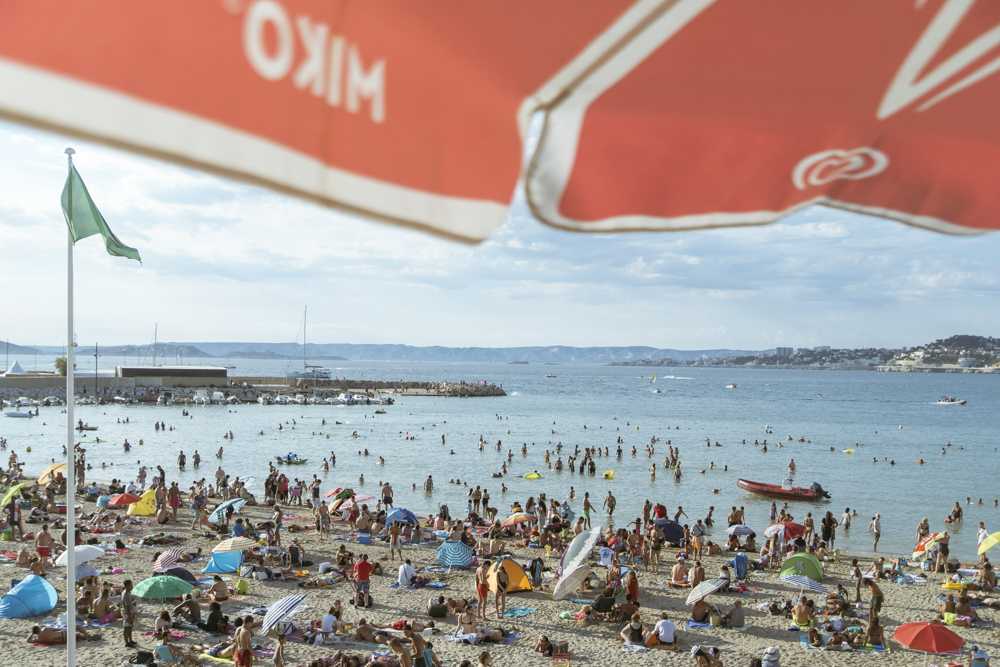 Une vue de la plage de la Pointe Rouge en une fin d'après-midi d'été, remplie de monde. 