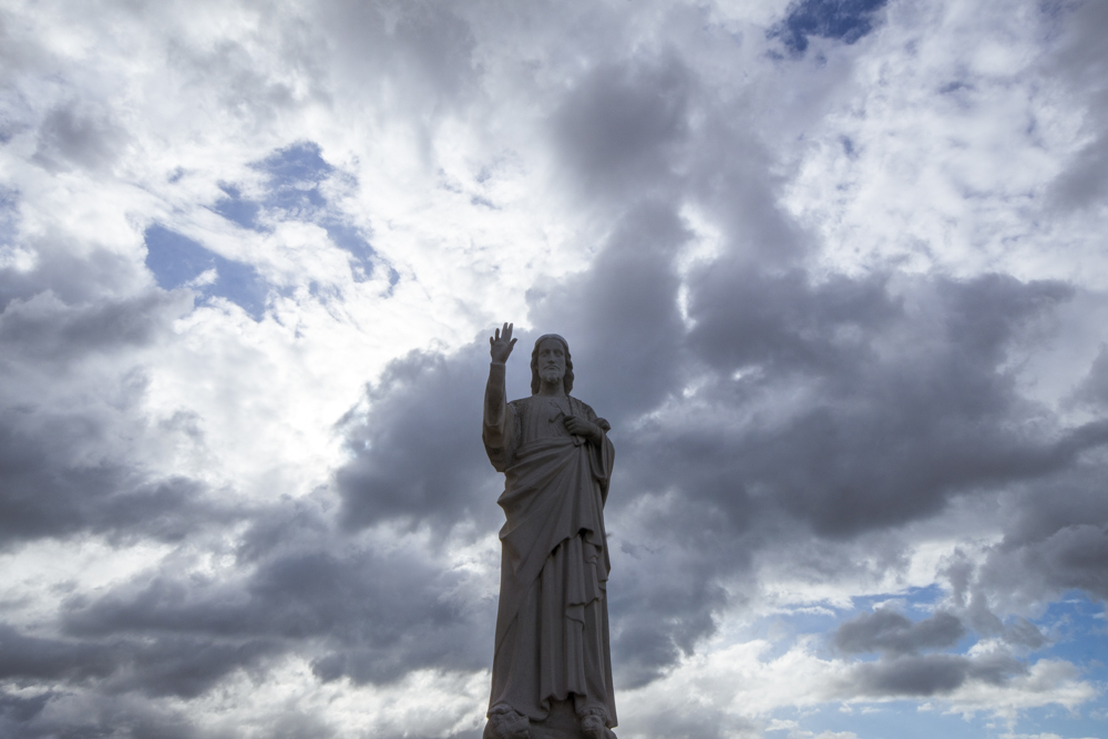 La statue du Christ sur la parvis de la basilique Notre-Dame de la Garde à Marseille sous un ciel nuageux.