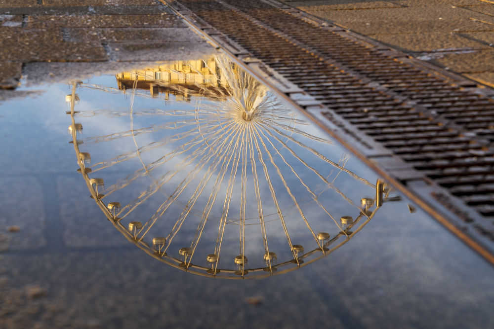 La grande roue se reflète dans une flaque d'eau sur le Vieux-Port de Marseille.