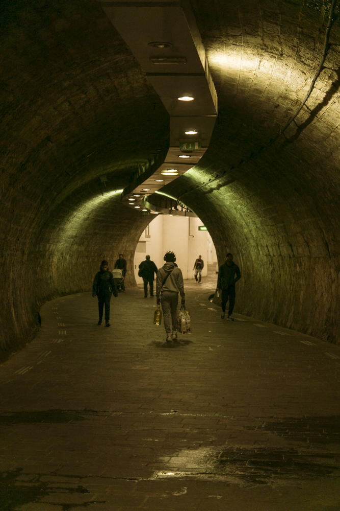 Des passants dans la pénombre du tunnel à la sortie de la station de métro Noailles à Marseille.