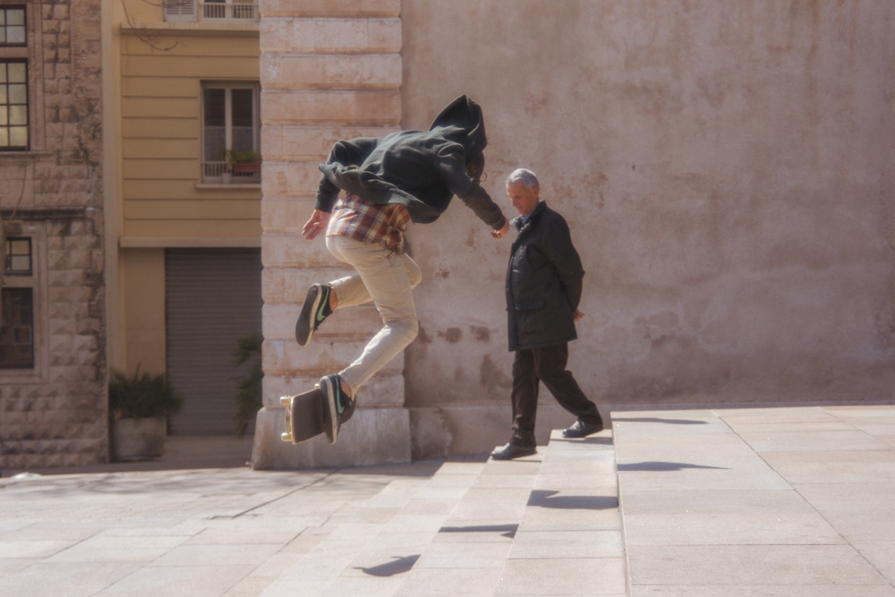 Un homme descend un escalier pendant qu'un skateur saute par dessus cet escalier.